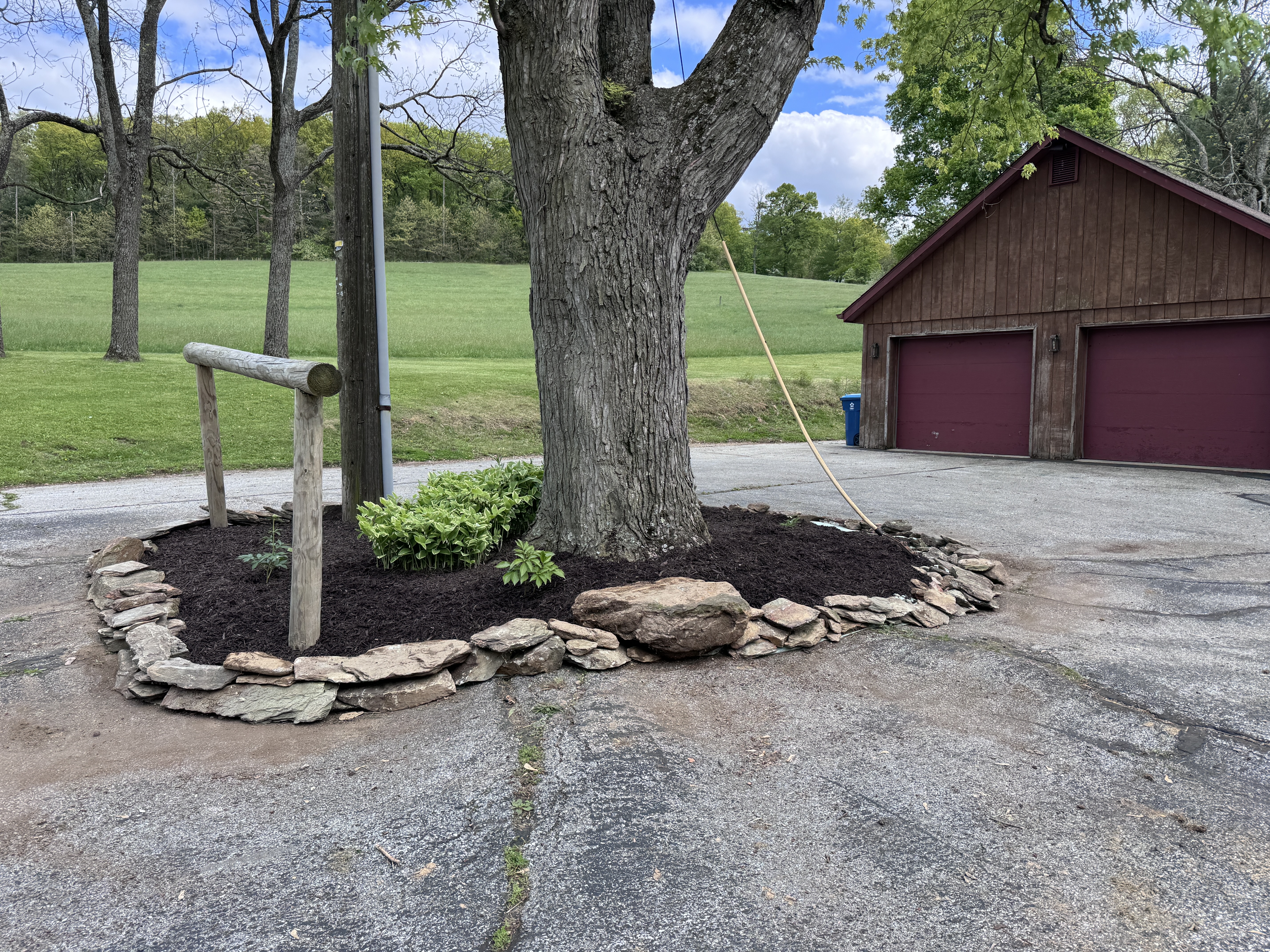 Wide final shot of the completed driveway island from across the drive, rope still hanging as a reminder of the day