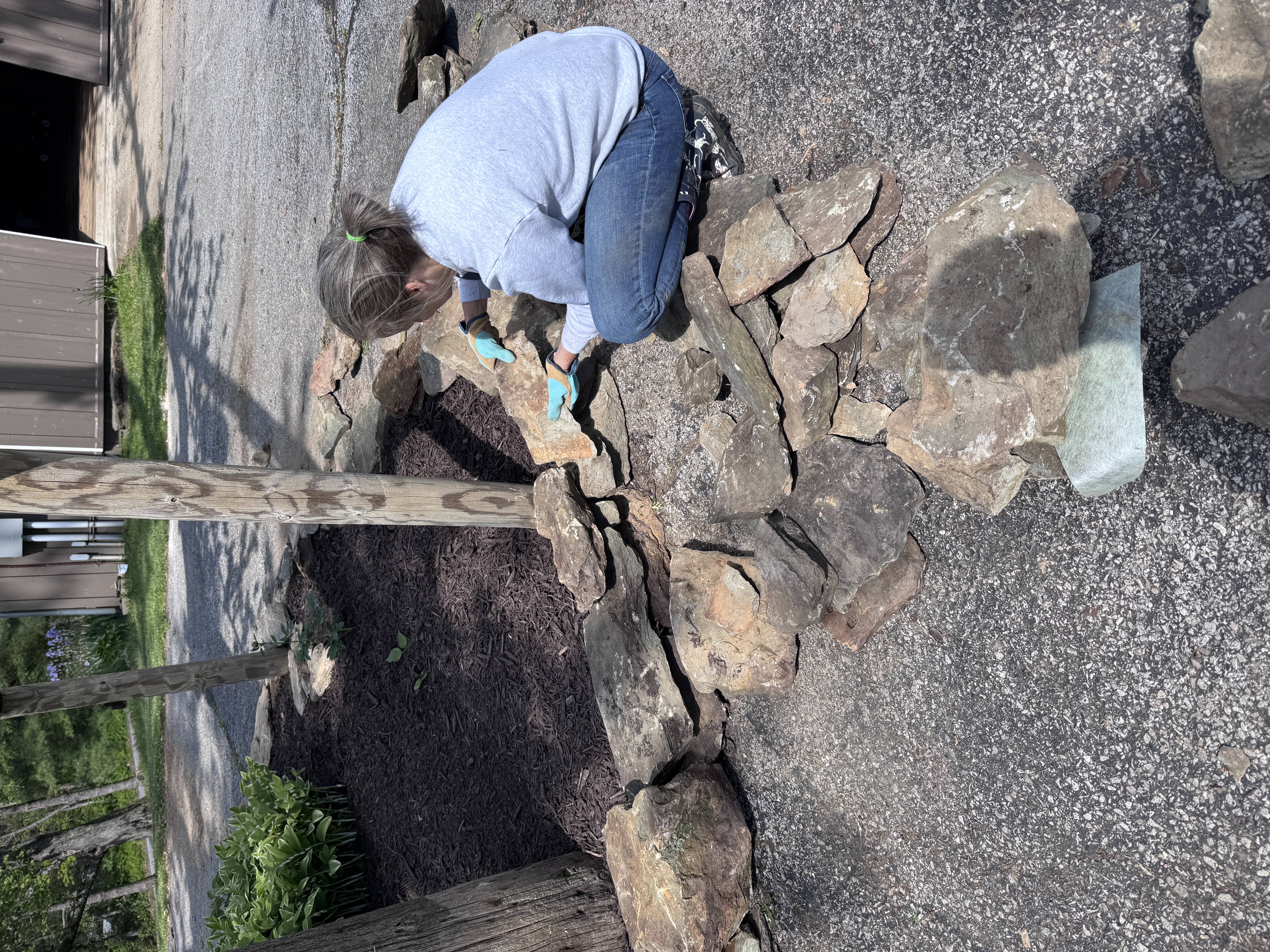 Amy kneeling at the island wall, fitting large new stones into the ring