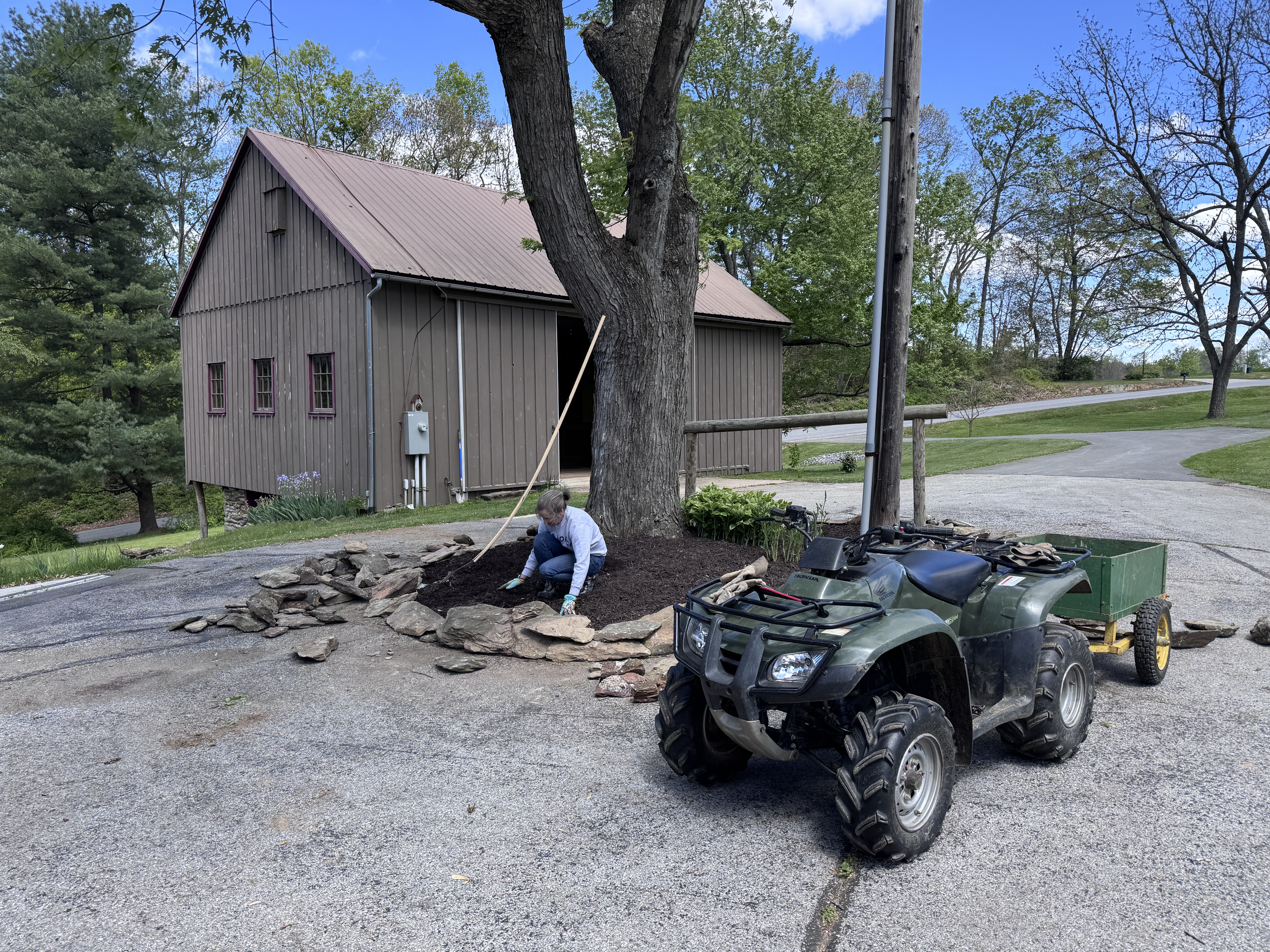 Amy kneeling at the island working on the wall, outbuilding and barn in background