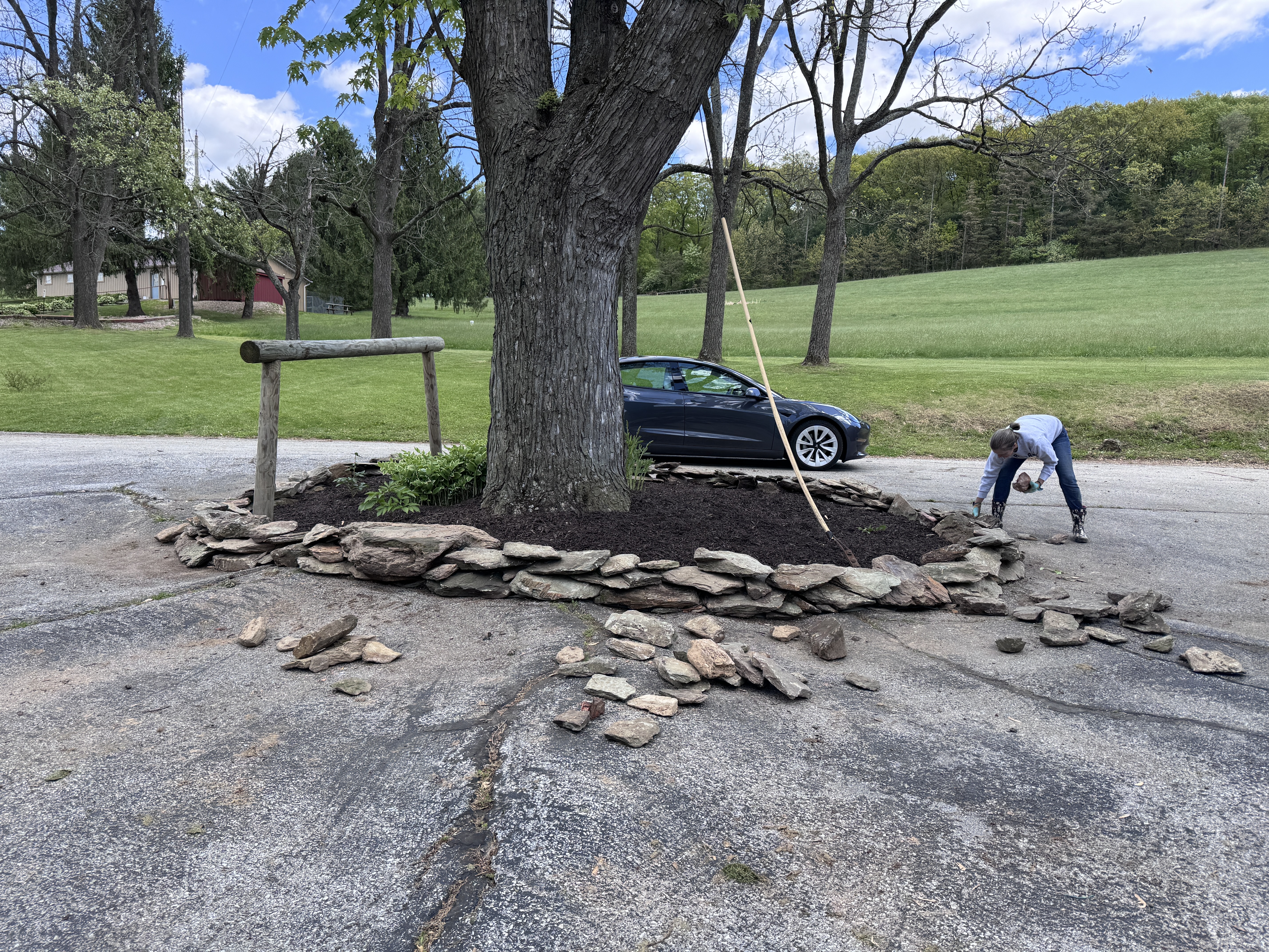 Amy bent over at the island wall, wall substantially taller and more complete, car visible on road behind